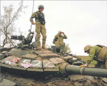  ?? UKRAINIAN Photograph­s by Leo Correa Associated Press ?? servicemen look over a destroyed Russian tank Saturday in an area near the Russian border in the Kharkiv region. A number of cities and villages have been retaken in a counteroff­ensive in the northeast.