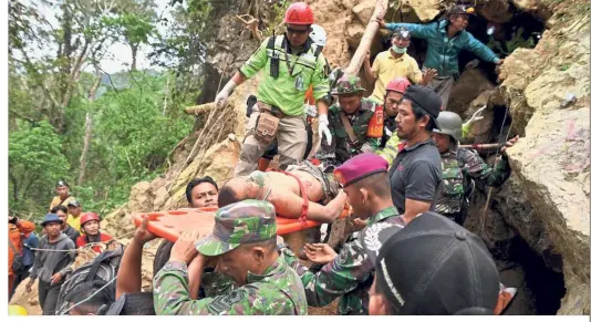  ?? — Reuters ?? In safe hands: Rescue workers carrying out a miner from the collapsed illegal gold mine at Bolaang Mongondow regency in North Sulawesi, Indonesia.