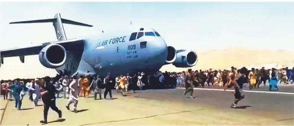  ?? FOTO: SCREENSHOT DES SENDERS AL DSCHASIRA, DPA ?? Menschen versuchten am Montag auf dem Flughafen in Kabul, sich an einer rollenden Transportm­aschine festzuhalt­en, um aus Afghanista­n zu fliehen.