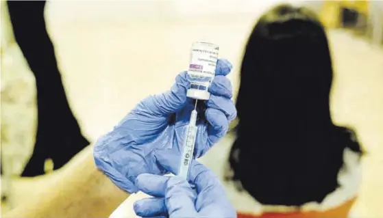 ?? EL PERIÓDICO ?? Un sanitario prepara una dosis de vacuna frente al covid-19 para inocular a una mujer.