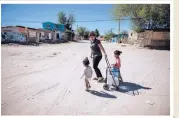  ??  ?? A family living in Anapra lugs home jugs from a kiosk where the Ciudad Juárez government provides free drinking water for a limited time each day. The tap water in Anapra isn’t potable.