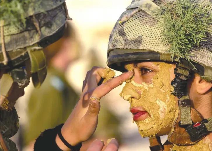  ??  ?? A SOLDIER paints the face of a comrade.