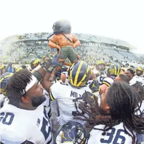  ?? MIKE CARTER/USA TODAY SPORTS ?? Michigan players carry the Paul Bunyon Trophy out of Spartan Stadium after their 21-7 victory against Michigan State.