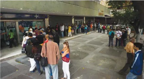  ??  ?? CARACAS: People queue outside a bank in Caracas in an attempt to deposit money. -—AFP