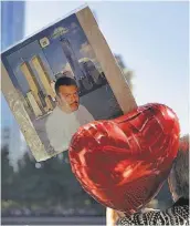  ??  ?? Recordator­io. Una personas sostiene un globo y la foto de su familiar fallecido en los atentados contra las Torres Gemelas, en 2001.
