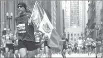  ?? Antonio Perez
/ Chicago Tribune ?? Thousands of runners, including a man running with a Mexican flag, takes part in the Chicago Marathon on Oct. 10, 2021.