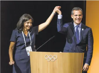  ?? Fabrice Coffrini / Getty Images ?? The mayors of the would-be host cities — Anne Hidalgo of Paris and Eric Garcetti of Los Angeles — share the podium and a victory pose after the IOC’s announceme­nt.