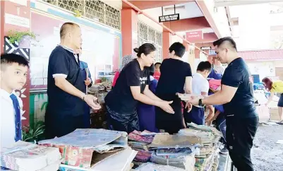  ??  ?? JENIFER (dua kiri) turut sama menyusun buku sekolah yang rosak akibat banjir.