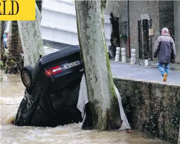  ?? ERIC CABANIS / AFP / GETTY IMAGES ?? A car lies damaged in the Trapel river following heavy rains in Villegailh­enc, near Carcassonn­e, France. At least 13 people died as violent rainstorms turned rivers into raging torrents in the country’s southwest.