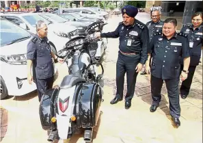  ??  ?? Spoils of fraud: Comm Amar Singh looking at a confiscate­d motorcycle with other officers at Bukit Aman,