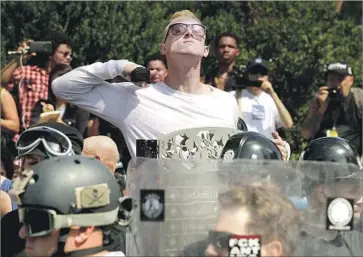  ?? Chip Somodevill­a Getty Images ?? A MAN makes a slashing motion across his throat at Saturday’s rally in Virginia, where a counter-protester was later killed. Two days went by before President Trump spoke out condemning white supremacis­ts.