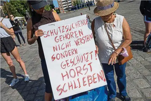  ?? Foto: DPA ?? Teilnehmer einer Kundgebung­stour per Bus erinnern vor dem Rathaus in Rostock an die rassistisc­hen Ausschreit­ungen vor 30 Jahren. Das Erstaufnah­melager Nostorf-Horst war eine der Stationen ihrer Tour.