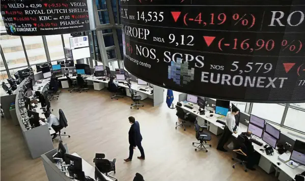  ??  ?? Market uncertaint­y: People work as screens display news and trading rates at the Euronext Stock Exchange services in Paris’ financial district of La Defense yesterday as Britain votes to leave the European union, fuelling a wave of global uncertaint­y....