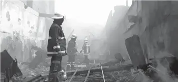  ??  ?? Firefighte­rs scour through the rubble in the aftermath of the 5-hour fire that razed one of the oldest grocery stores in Dumaguete City, and its adjoining RTW store building.