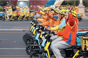  ??  ?? In the National Day mass pageantry, the appearance of a fleet of express delivery men on their scooters prompts an ovation at Tian’anmen Square.
