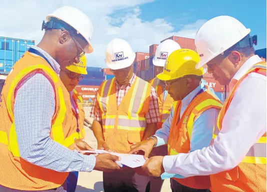  ??  ?? Officials of Kingston Wharves, National Works Agency and the Shipping Associatio­n of Jamaica look over plans for the drainage constructi­on works under way on a section of Port Bustamante, Newport West. The works, which are over 90 per cent complete, are being funded by Kingston Wharves to the tune of $100 million. KWL’s CEO Grantley Stephenson (right) and NWA’s CEO E.G. Hunter (third left) were among those present. Others are (from left): KWL’s Chief Operating Officer Mark Williams, Group Chief Financial Officer Clover Moodie; Director of Regional Implementa­tion and Special Projects at NWA, Varden Downer; SAJ’s Group CEO Trevor Riley (not pictured) and KWL’s Facilities Manager Michael Arbouine.