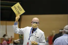  ?? TED S. WARREN — THE ASSOCIATED PRESS ?? Dr. John Corman, the chief clinical officer for Virginia Mason Franciscan Health, holds a sign that reads “Need Vaccine” to signal workers to bring him more doses of the Pfizer vaccine for COVID-19 as he works at a one-day vaccinatio­n clinic set up in an Amazon.com facility in Seattle.