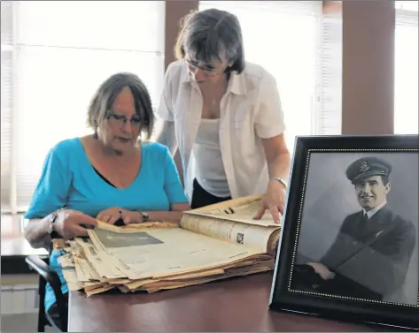  ?? MILLICENT MCKAY/JOURNAL PIONEER ?? Barbara Reed, left, and Edith French look through an April 1948 edition of the Summerside Journal newspaper. On the front page was their parents’ marriage notice. At right is a photo of Mungall in his Air Force uniform.