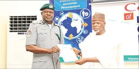  ??  ?? Controller, Tincan Area Command, Customs, Bashar Yusuf, (left); receiving a letter of commendati­on by the World Customs Organisati­on from the Comptrolle­r-general of Nigeria Customs Service, Ahmeed Ali, in Abuja.