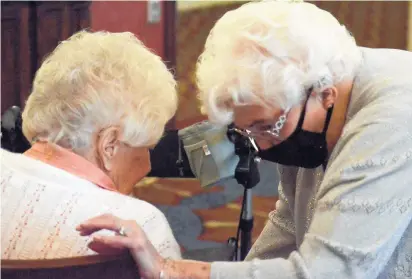  ?? JEFF VORVA/DAILY SOUTHTOWN PHOTOS ?? Lorraine Kane, right, helps her friend Gloria Chyrschel into a chair as the two celebrated their 100th birthdays last week at Smith Crossing in Orland Park.