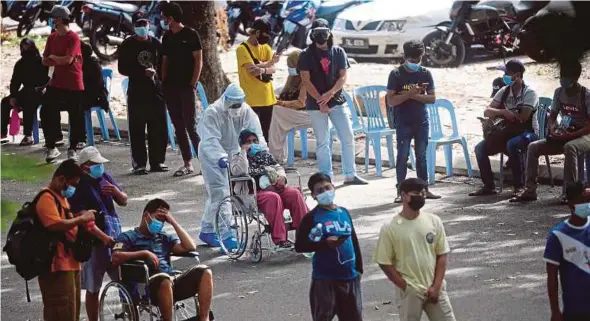  ?? BERNAMA PIC ?? A health frontliner (centre) assisting a Covid-19 patient at the Shah Alam Stadium Covid-19 Assessment Centre yesterday.