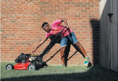  ?? KAITLIN MCKEOWN/STAFF ?? Phoenix Browne, 12, starts a lawnmower outside of his home in Chesapeake on Wednesday. This summer, Browne completed a challenge by the organizati­on Raising Men Lawn Care Service to cut 50 lawns for veterans, single parents, the elderly and people with disabiliti­es at no cost.