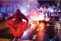  ?? AFP PHOTO ?? BURN AFTER WINNING
A man holds the Moroccan flag as scooters burn in the back on the sidelines of the live broadcast of the 2022 FIFA World Cup Group F football match between Belgium and Morocco in the former’s capital Brussels on Sunday, Nov. 27, 2022.