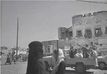  ?? AP Photo/Nariman El-Mofty ?? ■ Women walk Feb. 12 past Saudi-led coalition backed forces leading the campaign to take over Hodeida as they patrol Mocha, a port city on the Red Sea coast of Yemen.