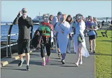  ?? 01_B02dook01 ?? Participan­ts at the head of the procession make their way along the promenade with face masks in honour of friends who could not make the dook this year.