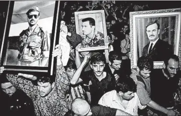  ?? HUSSEIN MALLA/AP 2000 ?? Syrian mourners wave portraits of President Hafez Assad, right, and his sons Bashar, center, and Basil, who died in 1994, to mourn the death of Hafez, in Damascus, Syria. Today, Bashar maintains an iron grip on a country that is in ruins.