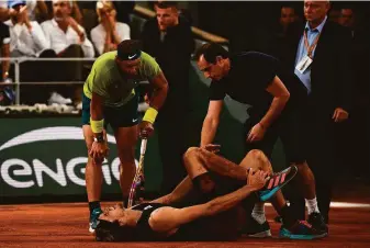  ?? Chrstophe Archambaul­t / Getty Images via TNS ?? Rafael Nadal checks on his French Open semifinals opponent, Alexander Zverev, who suffered an apparent ankle injury during the match. Zverev had to retire, sending Nadal to the final.