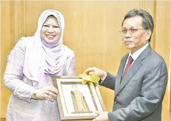  ??  ?? Rina (left) presenting a souvenir to Shafie.