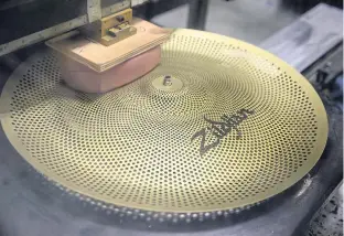  ??  ?? A cymbal is stamped with a logo at the Zildjian factory.