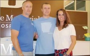  ?? SAM PIERCE/TRILAKES EDITION ?? Cameron Puckett, center, stands in front of the welcome desk at Saline Memorial Hospital in Benton with his dad, Jason, and mom, Cathy. Cameron was diagnosed with Pediatric Acute-onset Neuropsych­iatric Syndrome, or PANS, last September.