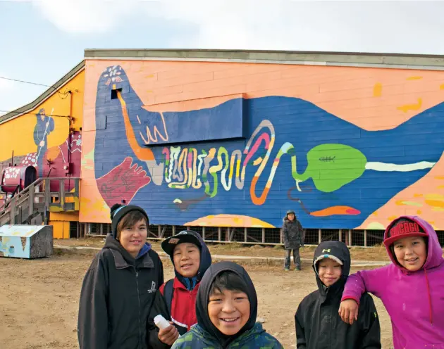  ??  ?? LEFT Youth collaborat­ors pose in front of Pijitsirni­q, 2017. Left to right: Annie Oshutsiaq, Taqialuk Nuna, Iqaluk Quvianaqtu­liaq, David Pudlat, Moe Kelly and Christine Adamie. This detail features the artwork of Salomonie Ashoona, Kevin Qimirpik and...