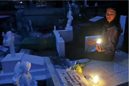  ?? Photo by Milo Brioso ?? FOR THE SOUL. A young lady offers candles on the tomb of her dearly departed at the Baguio Cemetery.