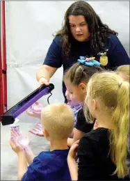  ?? Westside Eagle Observer/MIKE ECKELS ?? Paige Barrett (top, center) uses an ultraviole­t light to show students the germs on their hands during the Farm and You program in the safe room at Decatur Northside Elementary on March 8.