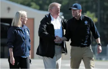  ?? AP PHOTO ?? U.S. President Donald Trump shakes hands with FEMA Administra­tor Brock Long as Homeland Security Secretary Kirstjen Nielsen watches after visiting areas in North Carolina and South Carolina impacted by Hurricane Florence on Wednesday in Myrtle Beach, S.C.