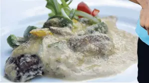  ??  ?? The mouth-watering pan-fried fish fillet in a pool of creamy coconut sauce.