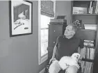  ?? LISA SCALFARO/AKRON BEACON JOURNAL ?? Jason Kolb looks at a charcoal drawing called “Sacred Ground” that hangs in his Kent home, while Daisy, the family’s dog, sits on his lap.