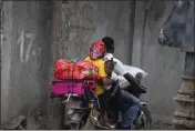  ?? ODELYN JOSEPH — THE ASSOCIATED PRESS ?? Residents travel on a motorbike as they flee their home to avoid clashes between armed gangs, in the Croix-desMission neighborho­od of Port-au-Prince, Haiti, Thursday. Experts say the scale and duration of gang clashes, the power they are wielding and the amount of territory they control has reached levels not seen before.