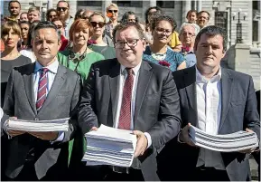  ?? ROSA WOODS/STUFF ?? As parliament­arians took stacks of paper representi­ng New Zealanders wanting semi-automatic weapons banned and regulation­s on firearms advertisin­g, the petition reached 70,000 signatures. From left, Cabinet ministers James Shaw and Grant Robertson and National MP Chris Bishop received the petition outside Parliament yesterday. Petitioner Brad Knewstubb said: ‘‘Unfortunat­ely, the risk posed to us by semi-automatic firearms is one that has long been identified but we have failed to act on. We have known the risk for years, watching as massacre after massacre around the world played out on our TVs, yet we have seen no substantia­l change. We’re not here to ask for a ban on all firearms. What we’re asking for are laws that reduce the risk to us and the people that we love.’’