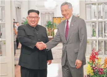  ?? GETTYIMAGE­S PHOTOS ?? After arriving in Singapore, North Korean leader Kim Jong Un is greeted by Singapore Prime Minister Lee Hsien Loong ( left) while President Donald Trump exits Air Force One at Paya Lebar Air Base on Sunday.