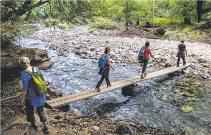  ?? Photos by Santiago mejia / The Chronicle ?? Hikers cross a footbridge on a bypass trail used to reach the Big Sur area isolated by the Pfeiffer Canyon Bridge closure.
