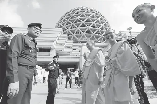  ?? — Gambar Reuters ?? DIPERMAINK­AN: Sekumpulan sami mengalu-alukan ketibaan anggota DSI sebelum pemeriksaa­n harian dijalankan ke atas tokong tersebut di wilayah Pathum Thani, kelmarin.