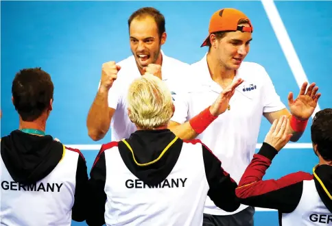  ?? — AFP photo ?? Tim Puetz (top C) and teammate Jan-Lennard Struff (top R) of Germany celebrate their victory with teammates following the World Group Davis Cup tennis third round doubles match against Matthew Ebden and John Peers of Australia at Pat Rafter Arena in...