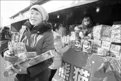  ?? CAO BOYUAN / FOR CHINA DAILY ?? Customers buy fireworks at an officially permitted store in Beijing on Thursday, ahead of the Spring Festival on Feb 8. The number of such stores has been reduced by nearly 25 percent year- on- year in the city to tackle air pollution.