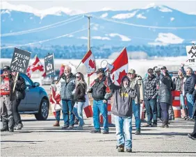  ?? JEFF MCINTOSH THE CANADIAN PRESS ?? Anti-carbon tax protesters wave signs as they block the Trans-Canada Highway down to a single lane near Calgary on Monday.