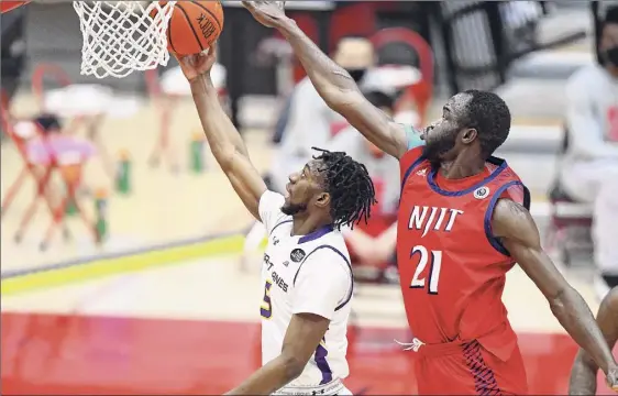  ?? Steve Mclaughlin / Hartford Athletics ?? Ualbany's Jamel Horton goes for a layup under the outstretch­ed arm of NJIT’S Antwuan Butler in their America East Tournament game Saturday in Hartford, Conn. Horton had 12 points and seven assists for the Danes in 36 minutes of playing time.