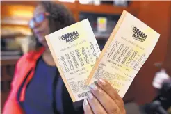  ?? MIKE STEWART/ASSOCIATED PRESS ?? A shop employee in Atlanta holds Mega Millions tickets on Monday. Nobody won the $1 billion jackpot in Saturday night’s drawing, which means the top prize for tonight’s Mega Millions draw is the world’s largest, at $1.6B.